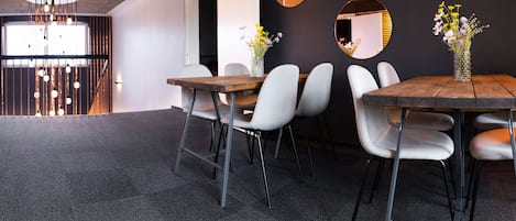 A modern conference room with a wooden table, grey upholstered chairs, and a vase of flowers.