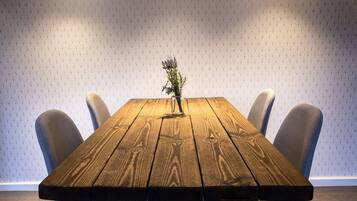 A wooden table with a vase of flowers in the center, surrounded by chairs.