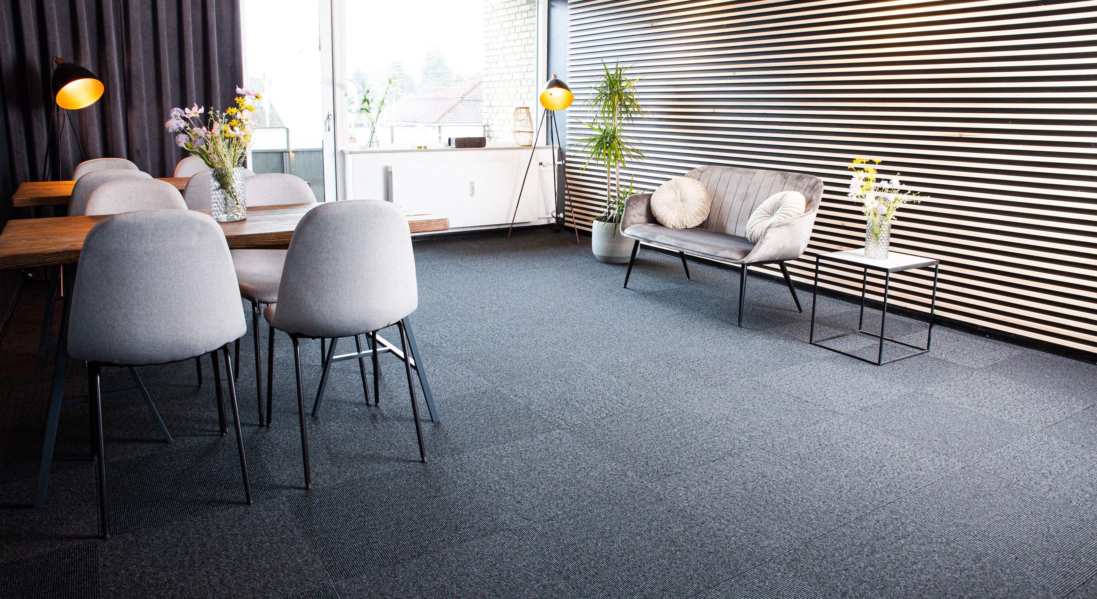 A modern office space with a meeting table, chairs, a sofa, and a potted plant.