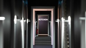 A hallway leading to a room labeled "KITCHEN" with a fire extinguisher on the wall.