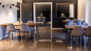 A modern conference room with a polished concrete floor, grey upholstered chairs, wooden tables, and black metal accents.