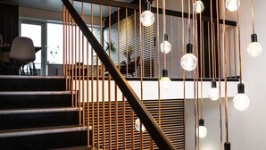 A staircase with a modern design, featuring a metal railing and hanging light bulbs.