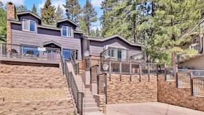 A multi-story house with a stone exterior, a deck with outdoor seating, and a staircase leading to the upper levels. - Circle Views #1602 (Big Bear Lake)