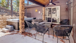 An outdoor patio with a stone pillar, a hot tub, and black wicker chairs. - Circle Views #1602 (Big Bear Lake)