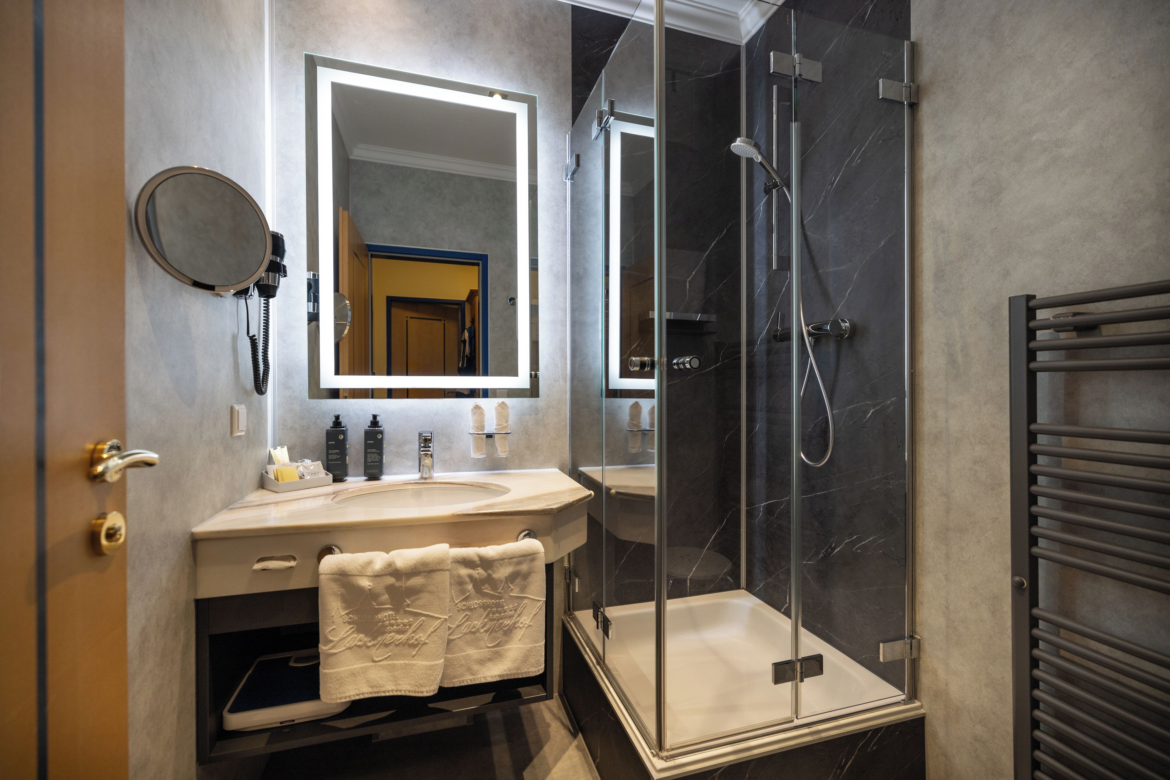 A modern bathroom with a glass-enclosed shower, a large mirror, and a vanity with a towel.
