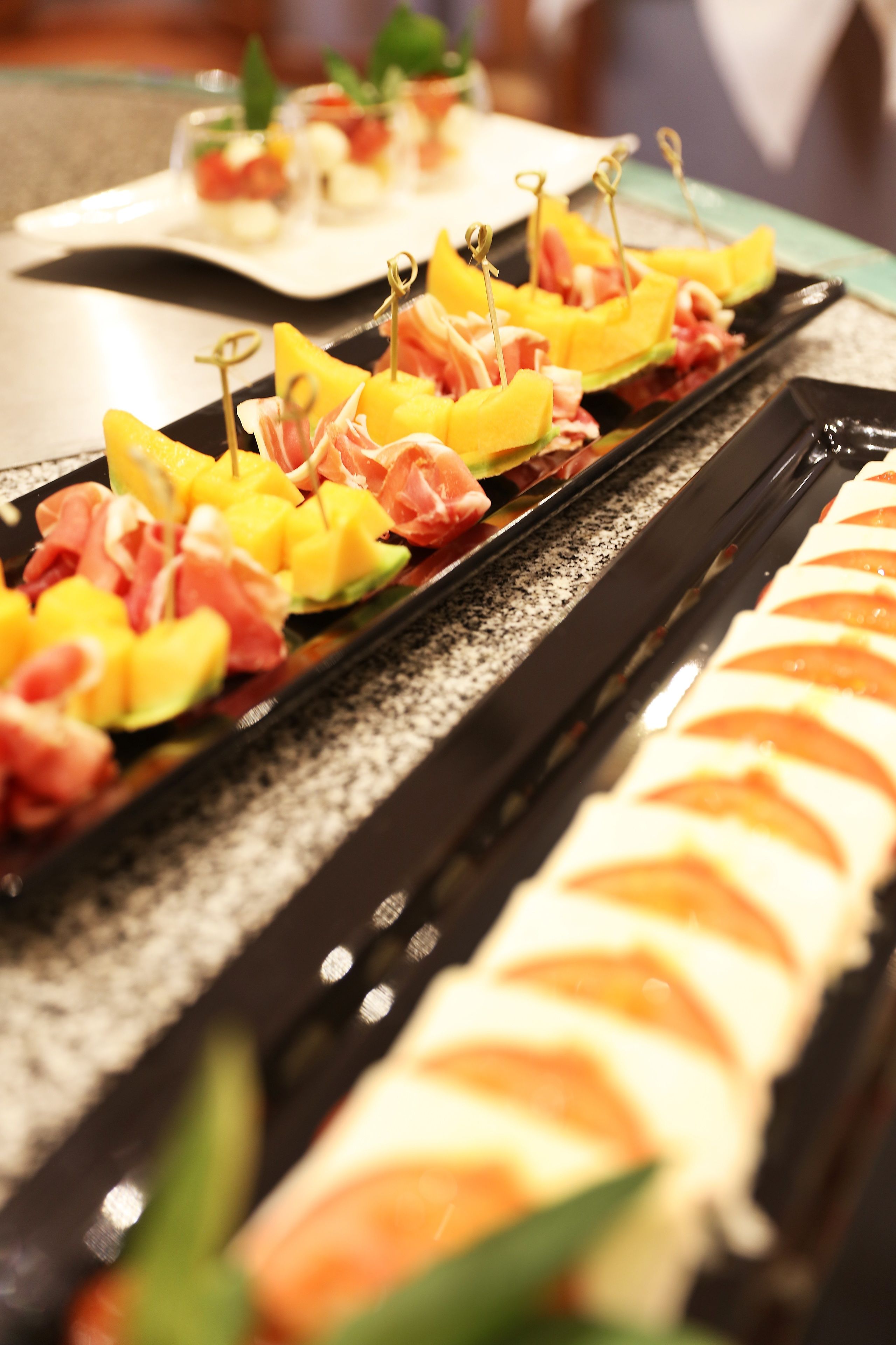 Un bufé con diferentes opciones de comida, como sushi, melón y brochetas de carne.