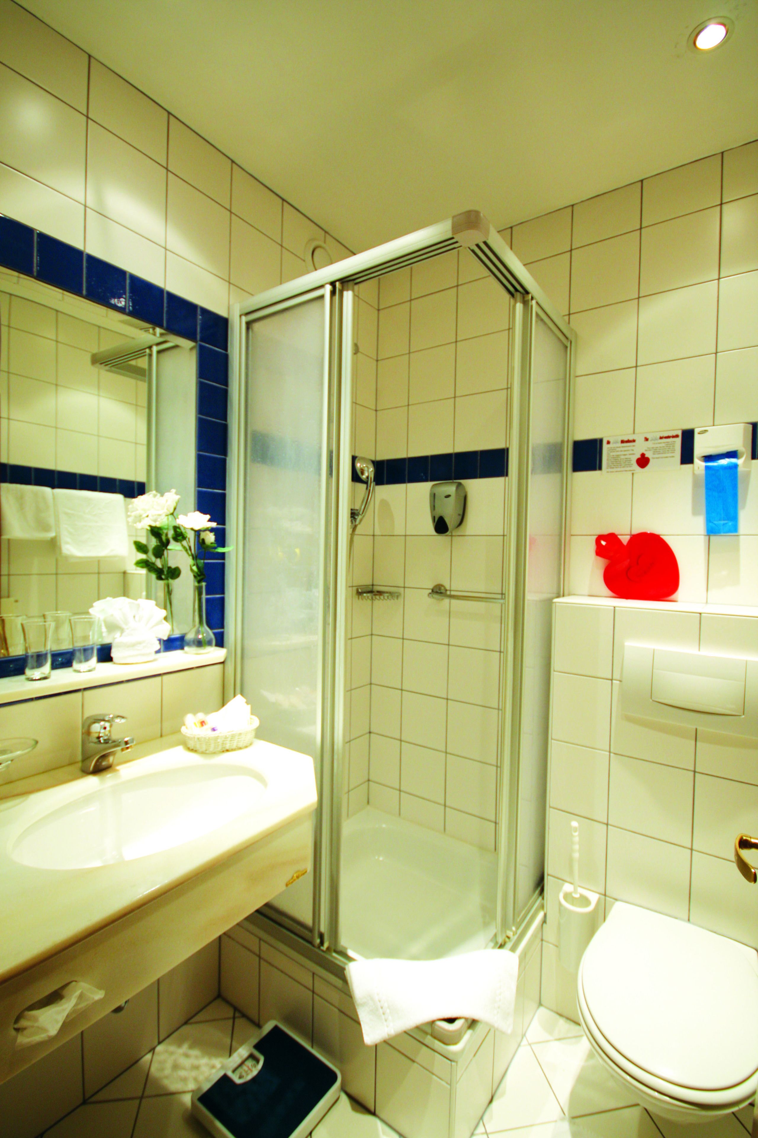 Un baño con cabina de ducha de vidrio, lavabo con toalla y retrete.
