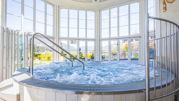 Un jacuzzi con vistas a un paisaje montañoso a través de amplios ventanales.