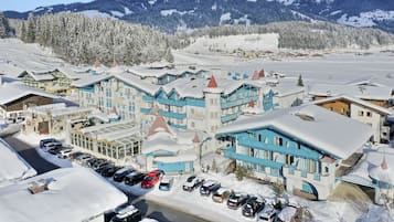 Un hotel cubierto de nieve con varias edificaciones, un estacionamiento y un paisaje montañoso.