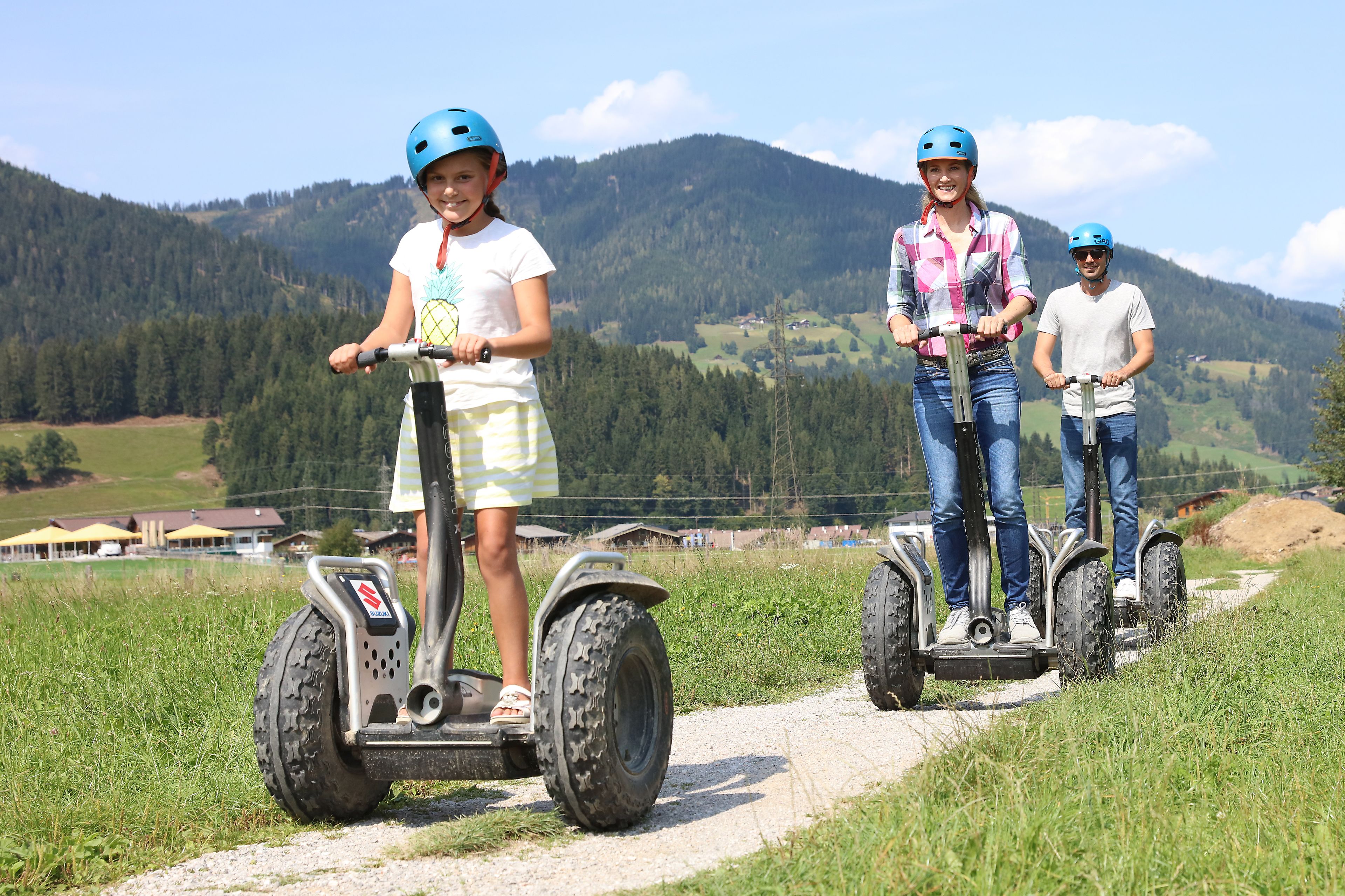 Tres personas en Segways por un camino con un paisaje montañoso al fondo.