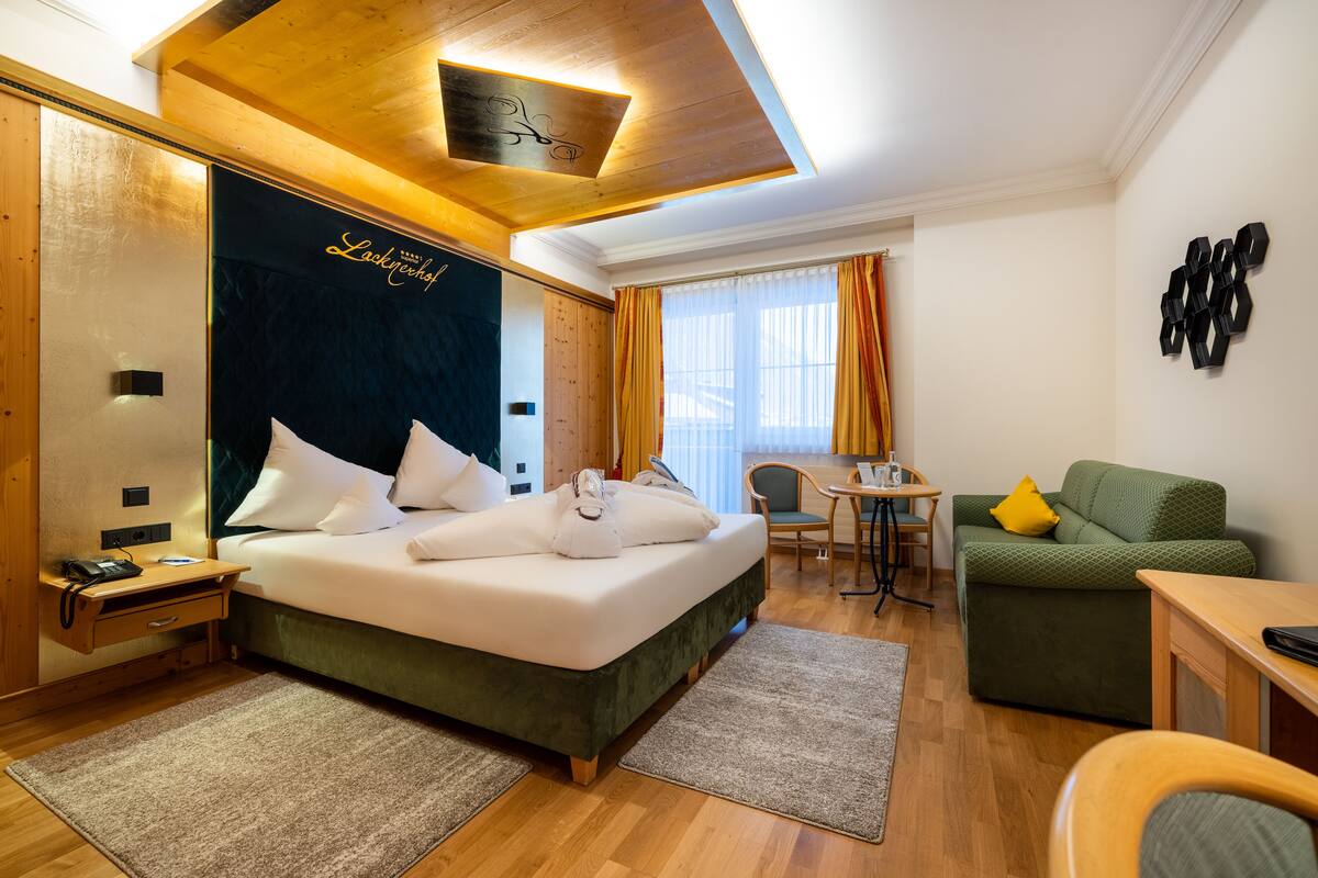 Une chambre d’hôtel avec un grand lit, un bureau, un canapé vert et une petite table.