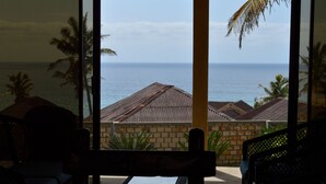 A view from a room with a large window overlooking a beach and ocean. - Salt Dune Lodge (Jangamo)