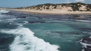 A beach with waves crashing onto the shore, a sandy beach, and a hill with sparse vegetation in the background. - Salt Dune Lodge (Jangamo)
