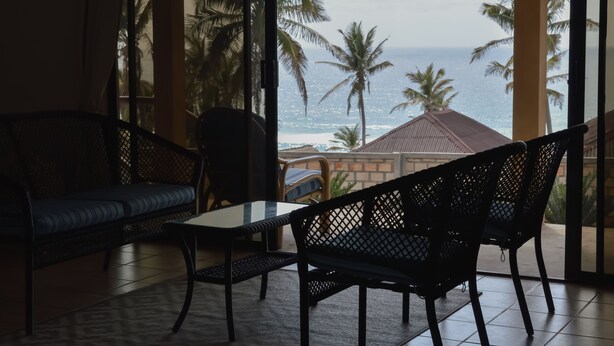 A room with a view of the ocean, featuring a sofa, a chair, and a table. - Salt Dune Lodge (Jangamo)