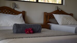 A hotel room with two beds, each with a wooden headboard, white bedding, and a small table between them. - Salt Dune Lodge (Jangamo)