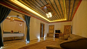 A room with a bed, a sofa, a television, and a decorative ceiling.