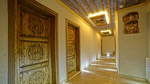A hallway with ornate wooden doors and a tiled floor.