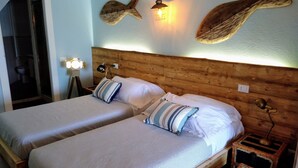 A double bed with striped bedding, wooden headboard, two bedside tables with lamps, and wall art. - La Calata (Portovenere)