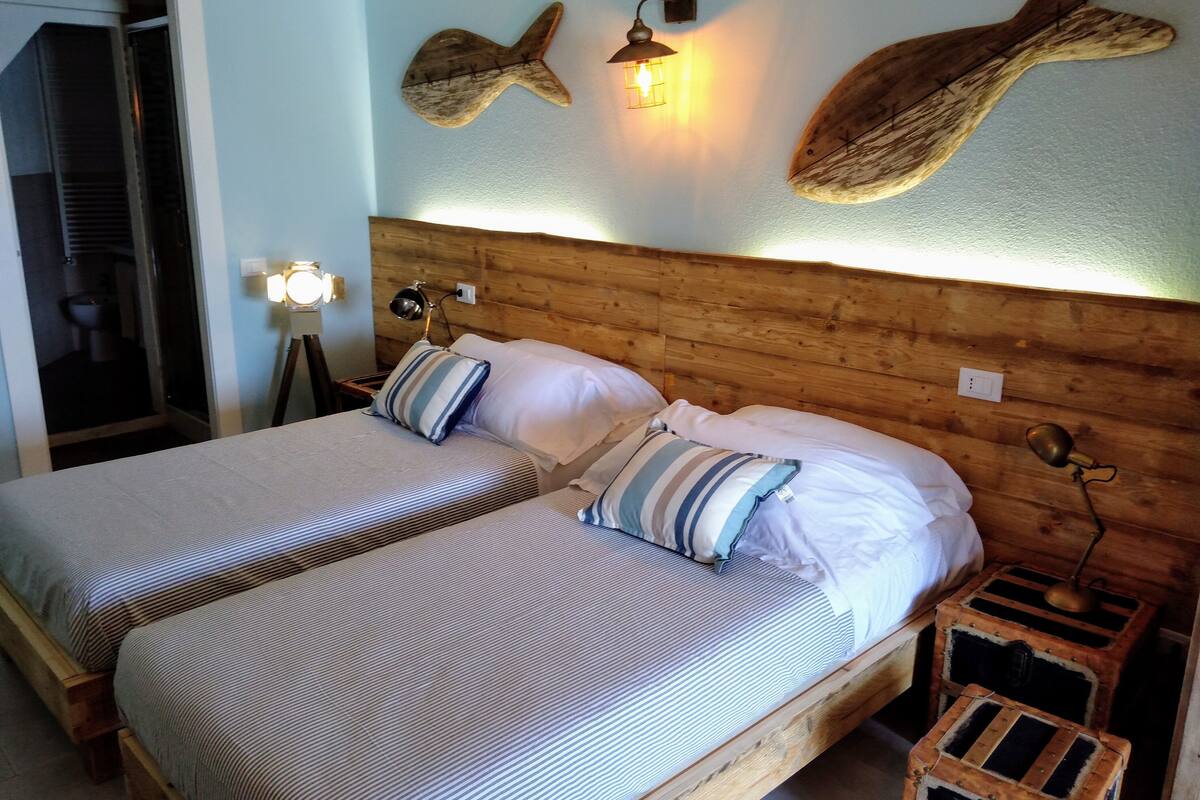 A double bed with striped bedding, wooden headboard, two bedside tables with lamps, and wall art.