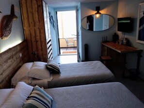 Une petite chambre agréable, dotée de deux lits, d’un bureau en bois, d’un miroir et d’une télévision.