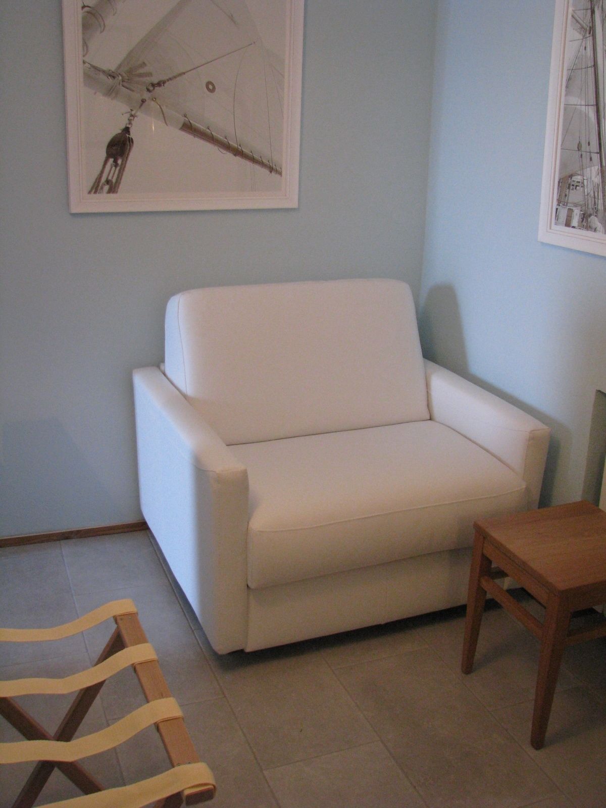 Une pièce avec un canapé blanc, une chaise en bois et une petite table en bois.