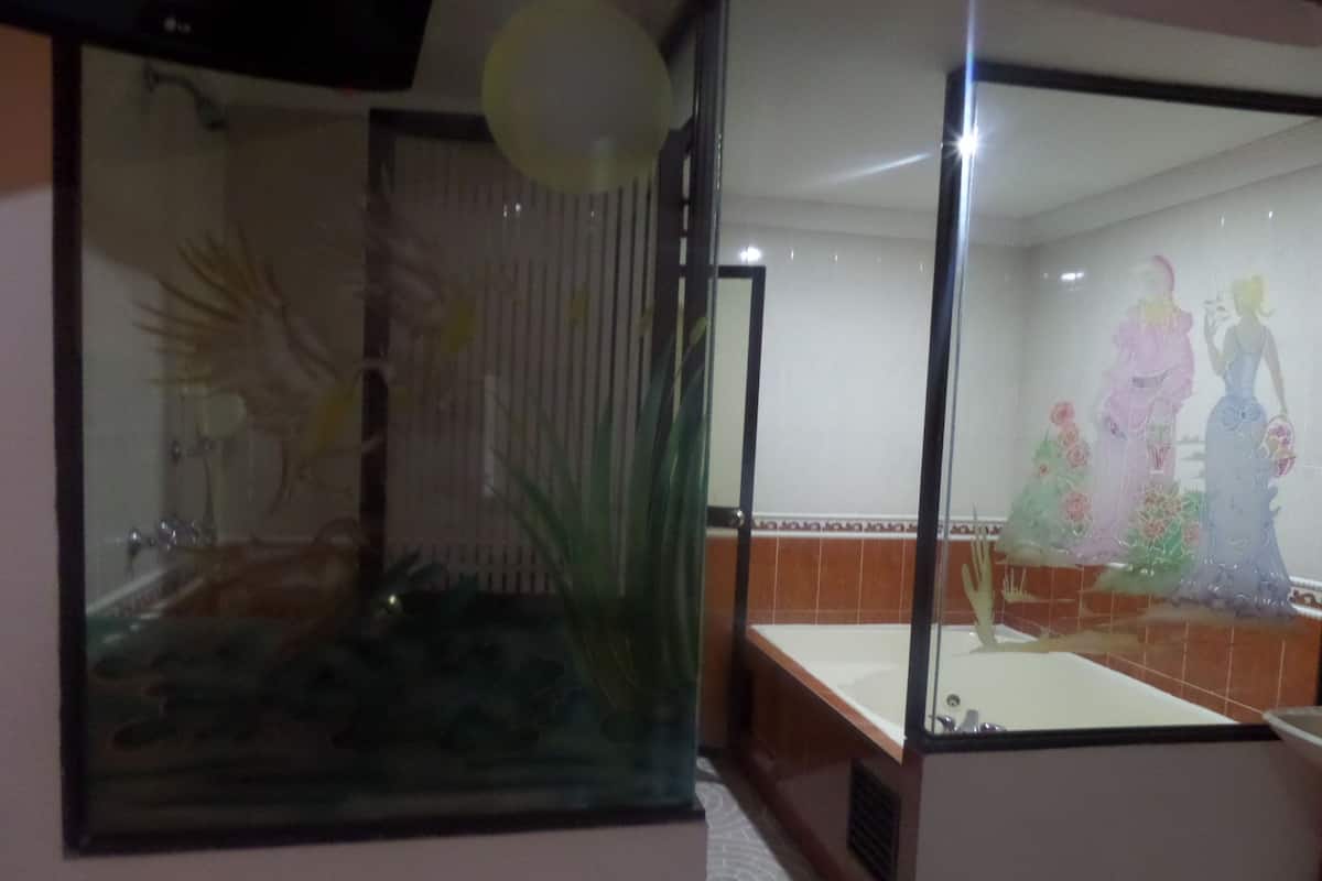 Ein Badezimmer mit Glastrennwand, einer Badewanne und einem Wandgemälde.