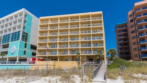 A beachfront hotel with multiple floors, a sandy beach in front, and a clear blue sky. - Emerald Skye 54 (Orange Beach)