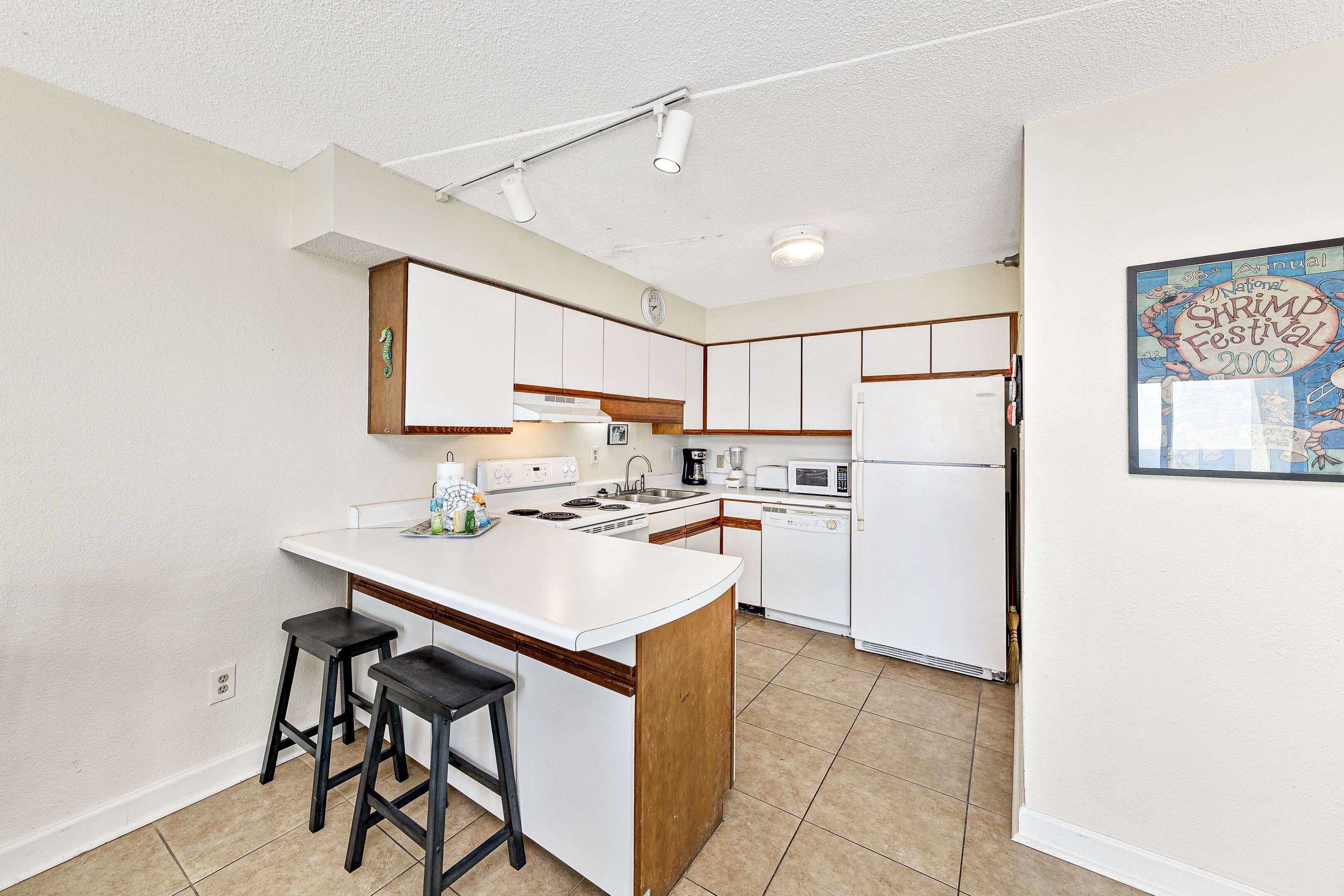 A modern kitchen with white cabinetry, a central island with stools, and a microwave.