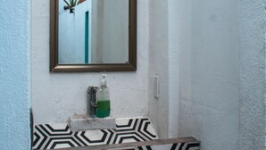Un baño con lavamanos blanco, un espejo y una lámpara de pared.