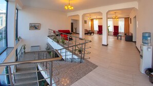 Amplia sala de estar con escaleras, asientos rojos y dispensador de agua.