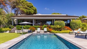 Una casa moderna con piscina, mobiliario exterior y jardines bien cuidados.