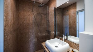 Un baño moderno con ducha de vidrio, un lavabo blanco y un espejo grande.