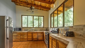 A kitchen with wooden cabinets, a stainless steel refrigerator, a microwave, and a stove. - Beachfront Villa Seabreeze with AC & Pool (Puerto Viejo)
