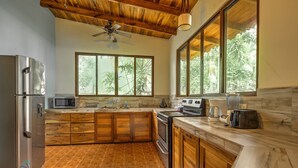 A kitchen with wooden cabinets, a refrigerator, a microwave, an oven, and a coffee maker.