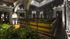 Eine großzügige Lobby mit hoher Decke, Marmorwänden und einer zentralen Bepflanzung.