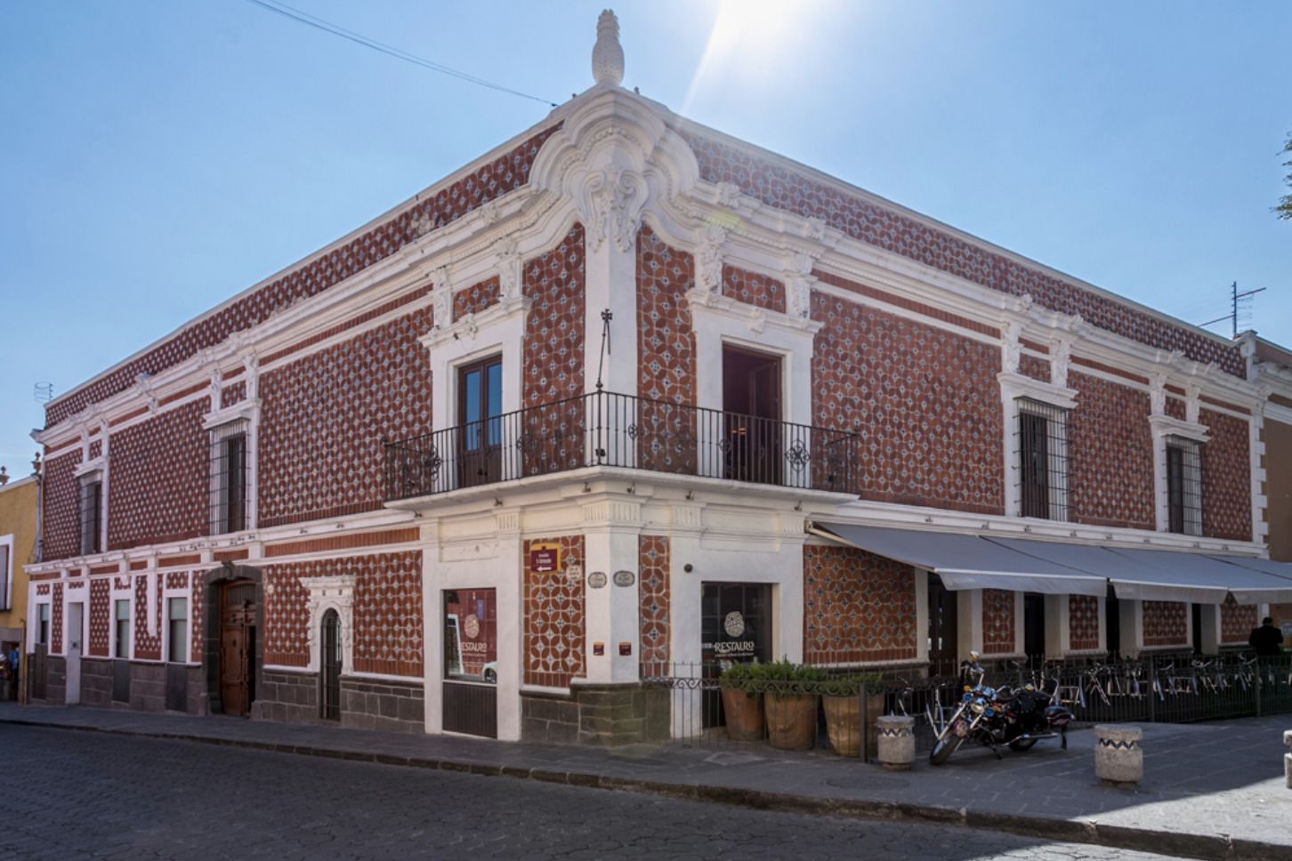 Un edificio histórico con fachada simétrica, un balcón y un cartel que indica un restaurante.