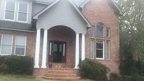 A two-story house with a front porch, brick exterior, and a small front yard. - Beautiful Home close to campus (Oxford)