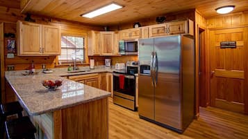 A wooden cabin-style kitchen with granite countertops, stainless steel appliances, and wooden cabinets.