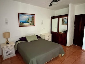 Une chambre à coucher avec un lit, une table de chevet, une commode, un miroir et un tableau accroché au mur.