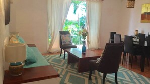 A living room with a sofa, two armchairs, a coffee table, and a dining area with chairs and a table.