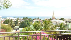 Vista des d'un balcó sobre una vila amb una església i una visió clara de l'oceà.