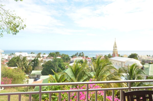 A coastal town with a prominent church spire, lush greenery, and a view of the sea. - HIBISCUS AND ITS PANORAMIC SEA VIEW (SAINTE-ANNE)