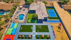 Ett flygbildsbild av ett bostadsområde med en swimmingpool, tennisbanor och en lekplats.