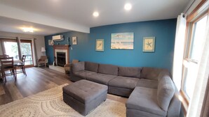 Ein Wohnzimmer mit Ecksofa, Kamin und großem Fenster.