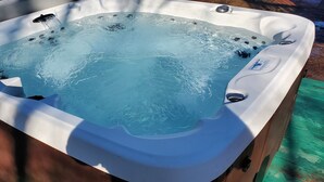 Ein Whirlpool mit glatter, blauer Wasseroberfläche, umgeben von einer Holzdielen-Terrasse.