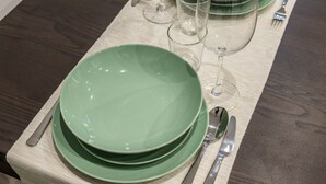 Una mesa de comedor con platos verdes, una copa de vino y cubiertos.