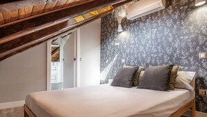 Ein Schlafzimmer mit einem hölzernen Bettgestell, einer neutralen Bettdecke und floraler Tapete.