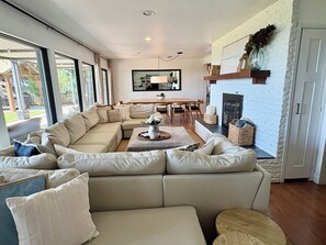 Una sala moderna con un sofá seccional, un comedor y una chimenea.