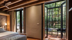A bedroom with a large bed, a ceiling fan, and a view of an outdoor patio with chairs and a table. - Morada La Noria (Puebla)