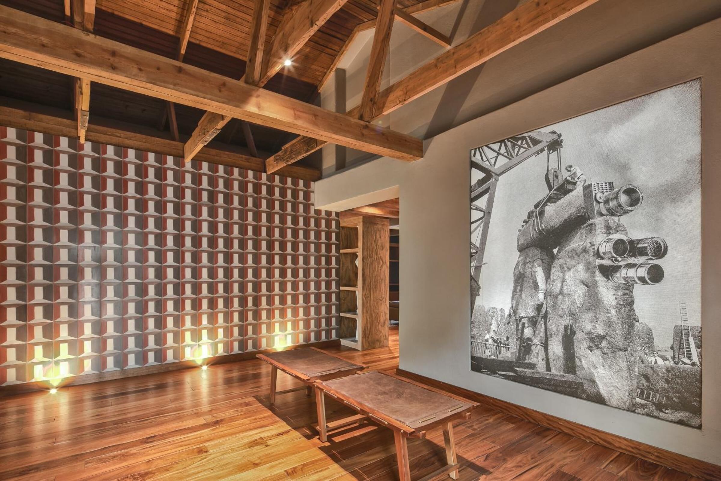 A room with wooden beams, a patterned wall, a large black and white artwork, and a bench.